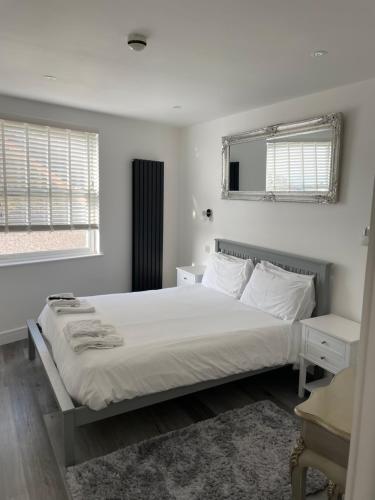 um quarto branco com uma cama e 2 janelas em Duporth Guest House em Penzance