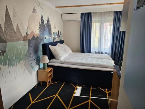 a small bedroom with a bed and a painting on the wall at Richmount Apartamenty Karpacz in Karpacz