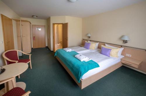 a hotel room with a large bed with purple and blue pillows at Hotel & Restaurant Zum Kap Arkona in Putgarten