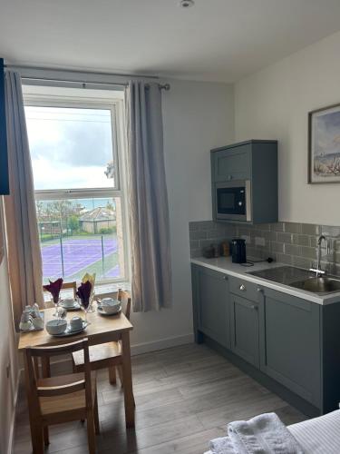 a kitchen with a small table and a window at Duporth Guest House in Penzance