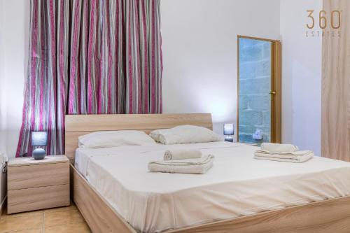 een slaapkamer met een groot bed en handdoeken bij Charming & Cosy 2BR home with WIFI in Birgu by 360 Estates in Birgu