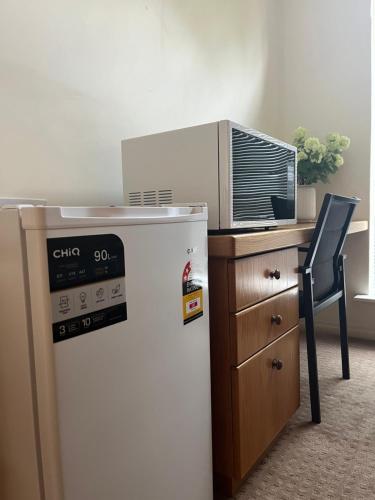a kitchen with a refrigerator and a desk with a microwave at Applecross 2 Bedrooms by Swan River in Perth