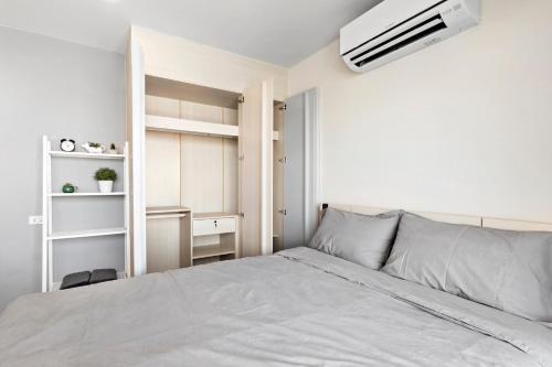a white bedroom with a bed and a white wall at Nidhra นิทรา in Ban Lat Krachaeng