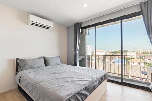 a bedroom with a bed and a large window at Nidhra นิทรา in Ban Lat Krachaeng