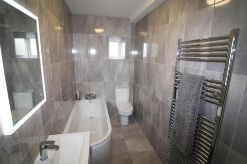 a bathroom with a tub and a toilet and a sink at Stylish Spacious 4 Bedroom House in Galway