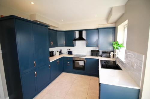 a blue kitchen with white counters and blue cabinets at Stylish Spacious 4 Bedroom House in Galway