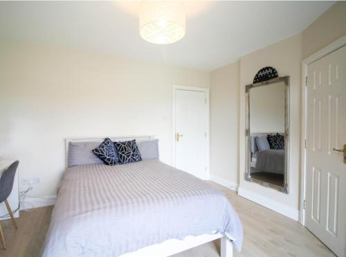 a white bedroom with a bed and a mirror at Stylish Spacious 4 Bedroom House in Galway