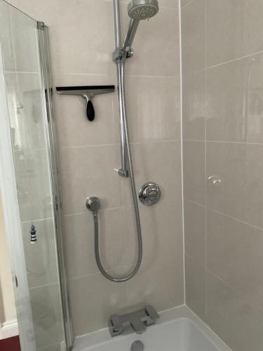 a shower with a glass door next to a bath tub at Private room in bright detached house in Salisbury