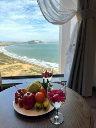 a plate of fruit and a glass of wine on a table at APEC MANDALA Condotel in Phan Thiet