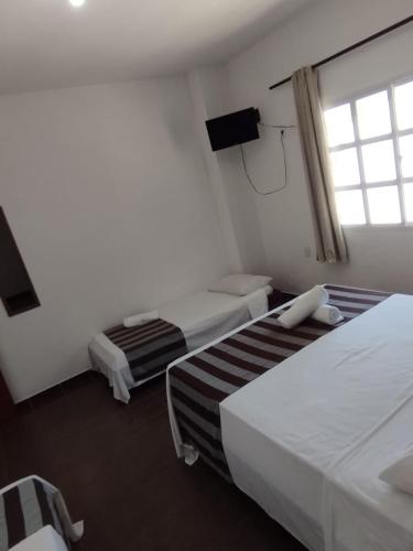 a hotel room with two beds and a window at Guarapousada in Guarapari
