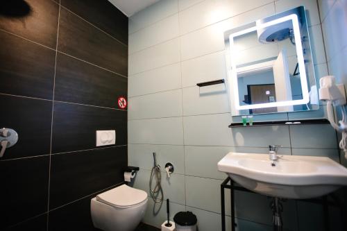 a bathroom with a sink and a toilet and a mirror at Andor Luxury Hotel & Duplex in Durrës
