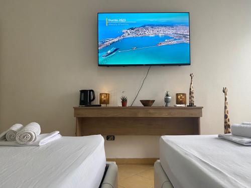 a room with two beds and a flat screen tv on the wall at Nicole Apartments Rental in Durrës