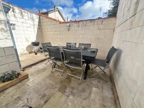d'une terrasse avec une table et des chaises devant un mur de briques. dans l'établissement L'idylle - Maison & Terrasse, à La Rochelle
