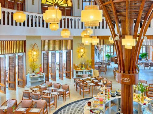 a restaurant with tables and chairs in a building at Le VIVA Resort Mui Ne in Mui Ne
