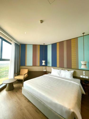 a bedroom with a large white bed and a chair at APEC MANDALA Condotel in Phan Thiet