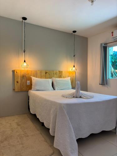 um quarto com uma grande cama branca e 2 luzes em Pituba Ville - Ap - 1 andar - 2/4 em Itacaré