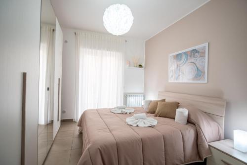 um quarto branco com uma cama grande e um cobertor rosa em KELIFOS Comfort Apartment em SantʼAgata di Militello