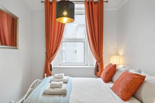um quarto com uma cama com cortinas cor de laranja e uma janela em Modern Flat on The Hoe w Private Parking em Plymouth