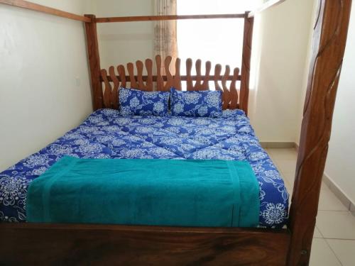 a bedroom with a wooden bed with blue comforter at Klimax Place in Kiambu
