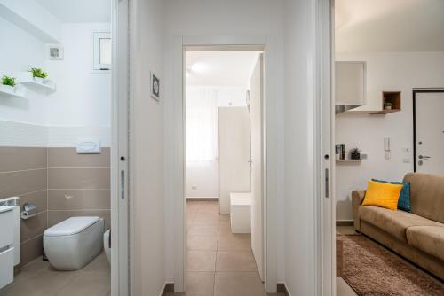 uma casa de banho branca com um WC e um sofá em KELIFOS Comfort Apartment em SantʼAgata di Militello