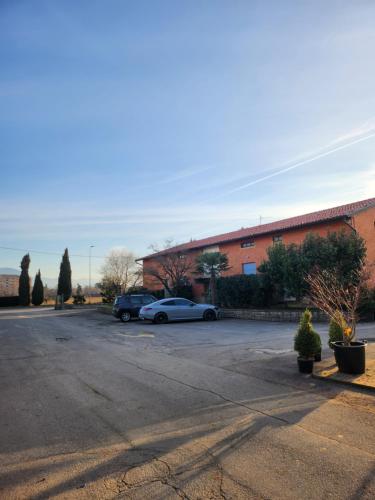 un estacionamiento con dos autos estacionados frente a un edificio en Agriturismo Il Vivaio en Bérgamo