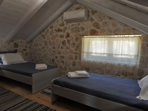 two beds in a room with a stone wall at Meganisi Villa Armonia - Private Pool Oasis in Vathí