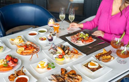 a woman sitting at a table with plates of food at Crowne Plaza Bangkok Lumpini Park by IHG in Bangkok
