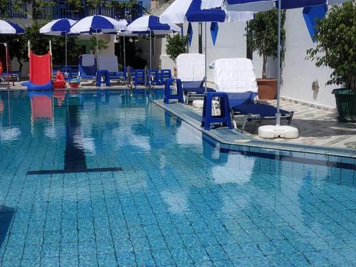a swimming pool with blue and white chairs and umbrellas at George Studios Stalida in Stalís