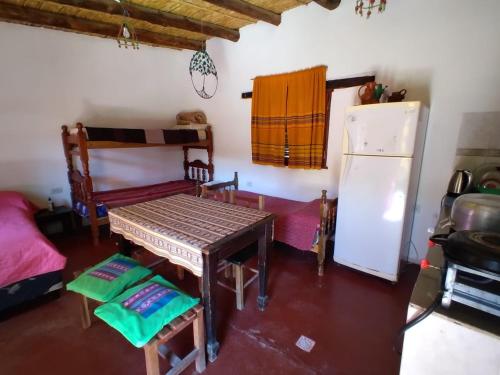 a living room with a table and a refrigerator at CABAÑAS LA LUCRECIA mono in Humahuaca