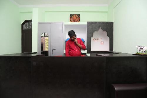 a man standing behind a counter talking on a phone at OYO Shree Palce in Ghaziabad