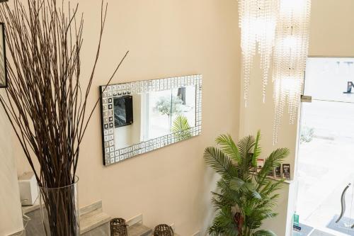 un miroir sur un mur dans une pièce ornée de plantes dans l'établissement Hotel Ilisia, à Thessalonique