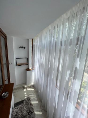 um quarto com uma grande janela com cortinas brancas em LNB ApartHotel Traian em Constança