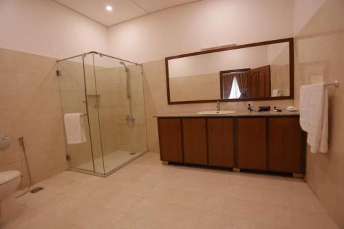 a bathroom with a shower and a sink and a mirror at A One Hotel Clifton in Karachi