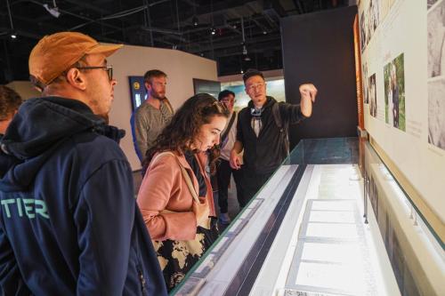 a group of people looking at a museum exhibit at Chengdu Local Tea Hostel - Short Walk To Taikooli - Chill & Social Coffee Lounge - Metro downstairs - Free Activities - Friendly English Speaking Staff - Tibet, Panda, Buddha & Snow Mountain Tours in Chengdu