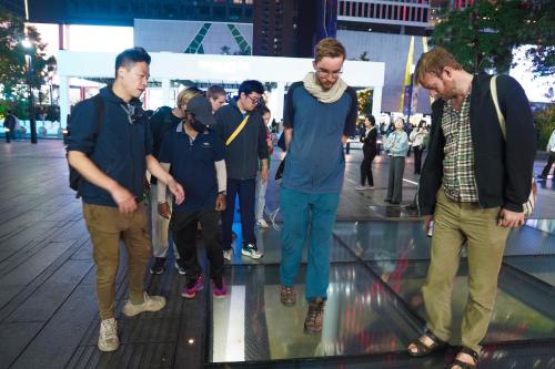 a group of men standing on a glass floor at Chengdu Local Tea Hostel - Short Walk To Taikooli - Chill & Social Coffee Lounge - Metro downstairs - Free Activities - Friendly English Speaking Staff - Tibet, Panda, Buddha & Snow Mountain Tours in Chengdu