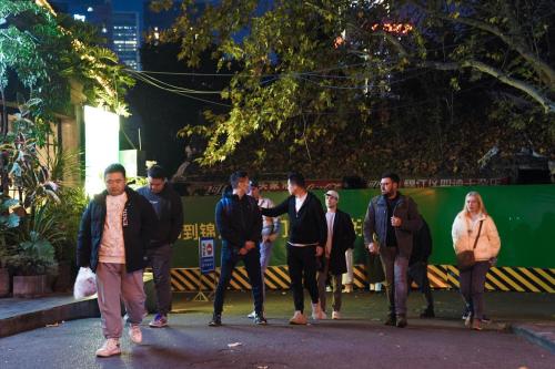 a group of people walking down a street at night at Chengdu Local Tea Hostel - Short Walk To Taikooli - Chill & Social Coffee Lounge - Metro downstairs - Free Activities - Friendly English Speaking Staff - Tibet, Panda, Buddha & Snow Mountain Tours in Chengdu