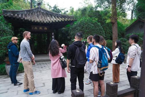 a group of people standing in front of a temple at Chengdu Local Tea Hostel - Short Walk To Taikooli - Chill & Social Coffee Lounge - Metro downstairs - Free Activities - Friendly English Speaking Staff - Tibet, Panda, Buddha & Snow Mountain Tours in Chengdu