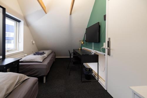 a room with two beds and a desk and a television at Kulukis Downtown Hostel in Nuuk