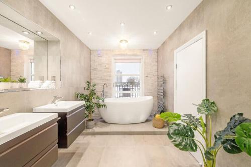 Luxurious & Spacious Townhouse في لندن: حمام مع حوض ومغسلتين والنباتات الفخارية