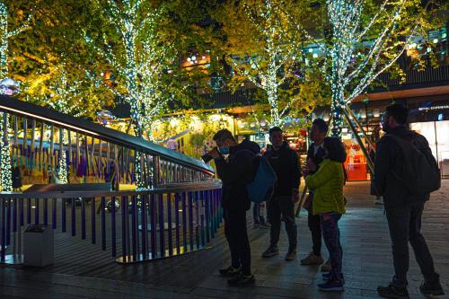 a group of people standing in front of a building with christmas lights at Chengdu Local Tea Hostel - Short Walk To Taikooli - Chill & Social Coffee Lounge - Metro downstairs - Free Activities - Friendly English Speaking Staff - Tibet, Panda, Buddha & Snow Mountain Tours in Chengdu