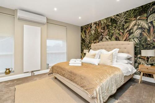 Luxurious & Spacious Townhouse في لندن: غرفة نوم بسرير كبير وورق جدران استوائي