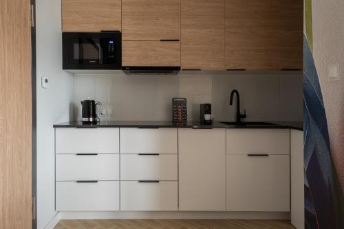 a kitchen with white cabinets and a microwave at AVAPARTS Apartament FAMILY in Jastarnia