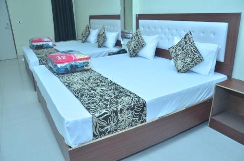 two beds in a room with white sheets and pillows at Divine sparrow family homestay in Agra