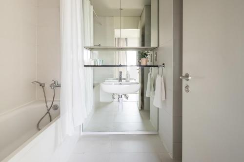 Frank Porter - Index Tower في دبي: حمام أبيض مع حوض وحوض استحمام