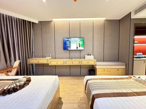 a hotel room with two beds and a tv on the wall at APEC MANDALA Condotel in Phan Thiet