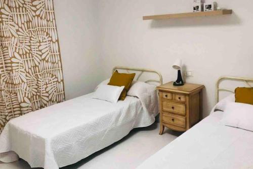 a bedroom with two beds and a wooden nightstand at Apartamento Andaluz CARMA in Torrox