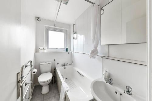 Baño blanco con aseo y lavamanos en No 15 Brompton cross, en Londres
