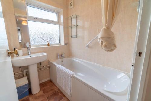 ein Badezimmer mit einer weißen Badewanne und einem Waschbecken in der Unterkunft Pass the Keys Stylish 3 bedroom home with free parking in Nottingham