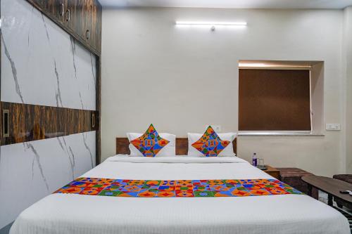 a bedroom with a large white bed with colorful pillows at FabHotel Perams Grand Inn in Kondapur