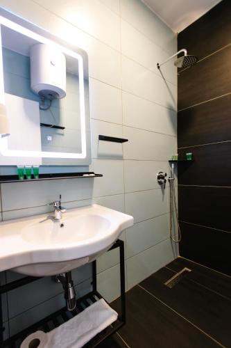 a bathroom with a sink and a mirror and a shower at Andor Luxury Hotel & Duplex in Durrës